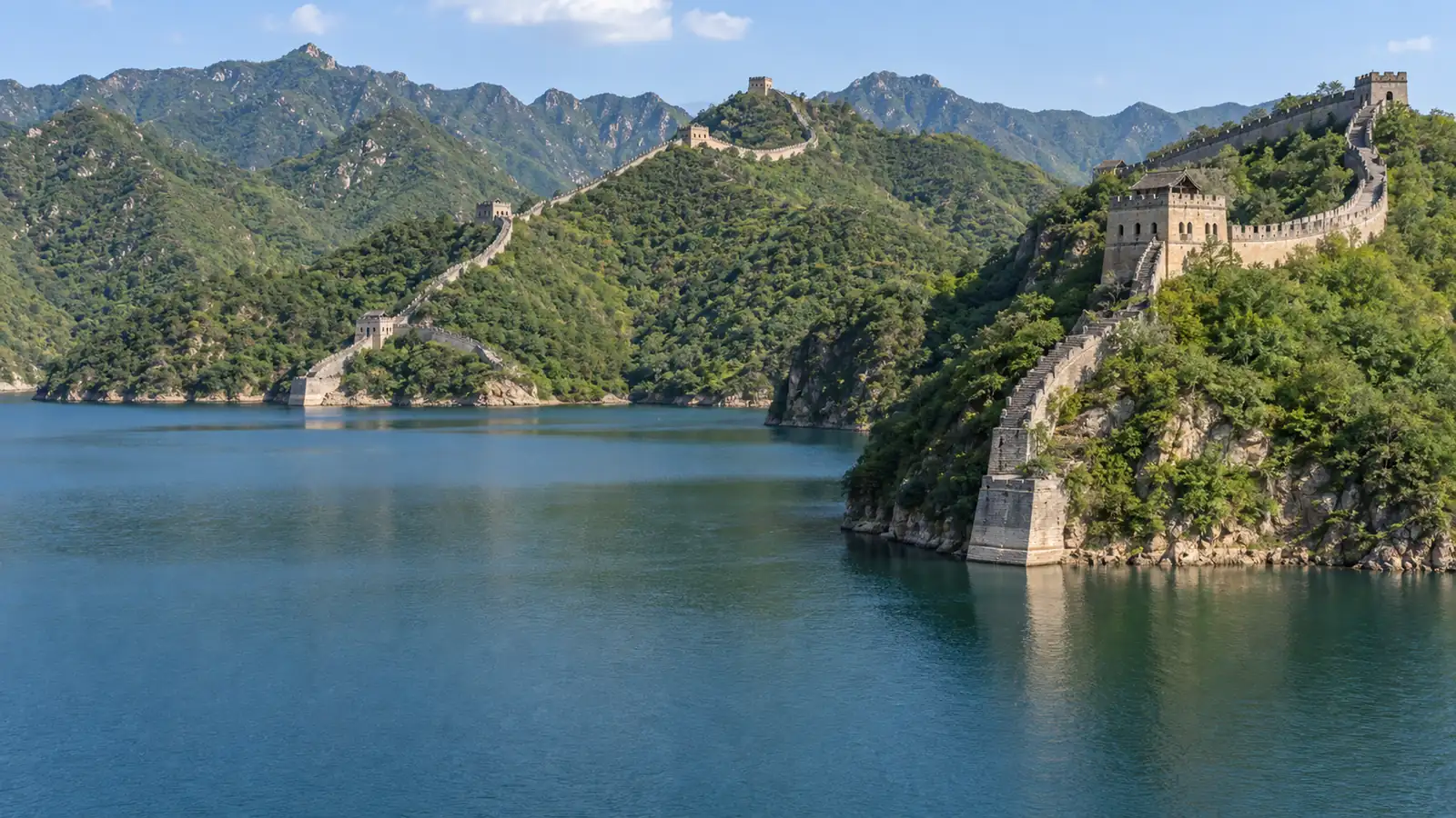 Huanghuacheng Great Wall descending across green ridges beside a reservoir