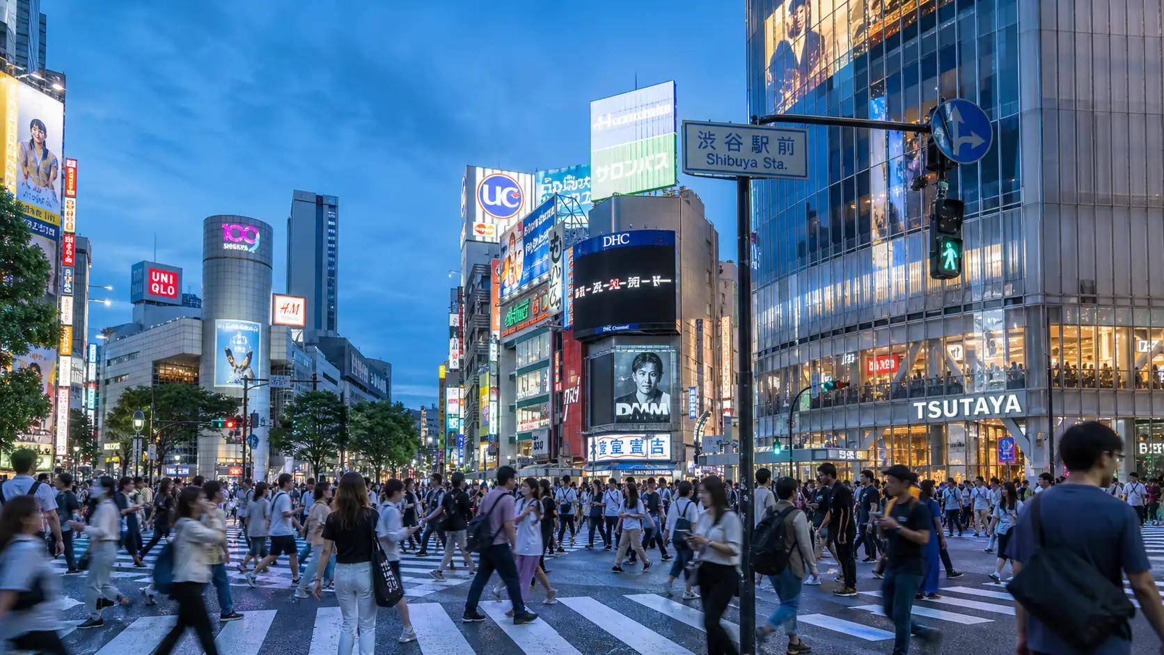 Evening pedestrian scene in Shibuya with station signs and city lights Evening pedestrian scene in Shibuya with station signs and city lights