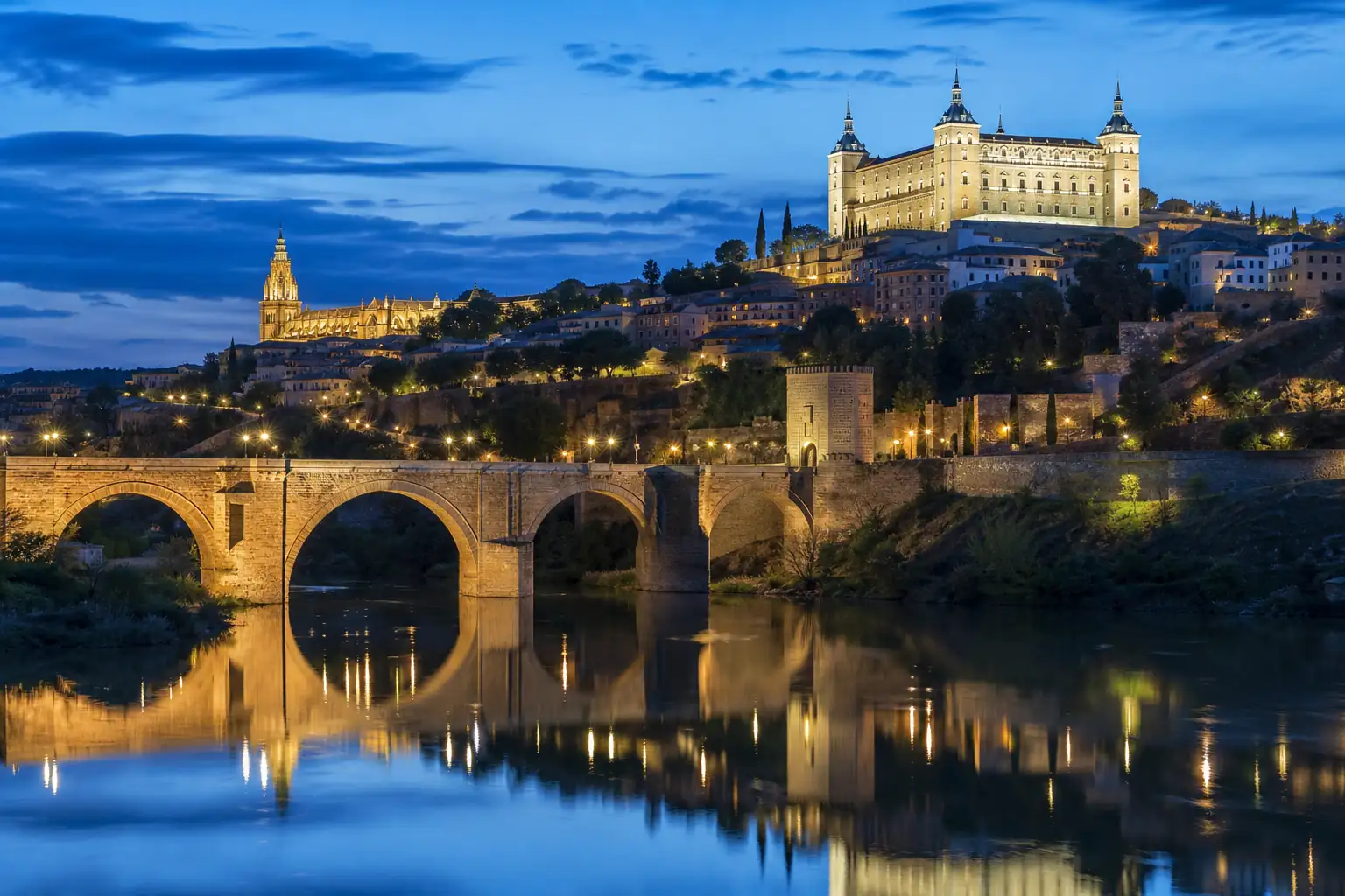 Toledo skyline and bridge reflected in the Tagus River at blue hour Toledo skyline and bridge reflected in the Tagus River at blue hour